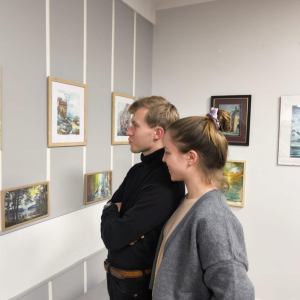 Na zdjęciu dwoje młodych ludzi ogladających z uśmiechem obrazy