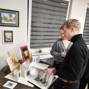 Na zdjęciu uczestnicy wernisażu przeglądający prace autora