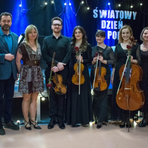 Na zdjęciu muzycy wraz z aktorami torzymskiego teatru "Pod trzema Gwiazdami" , w tle scena z napisem "Światowy Dzień Poezji". Patrząc od lewej strony ustawieni są aktorzy: Zofia Moręgiel, Michał Taszarek. Karolina Kieszewicz. Następnie muzycy Urban Quartet: Mateusz Makuch, Weronika Podkul, Natalia Rychlik, Natalia Makuch oraz dyrektora biblioteki Justyna Busler i wolontariusz Michał. 