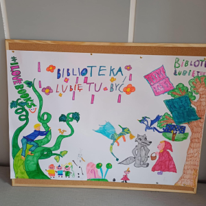 Na zdjęciu kolorowy plakat stworzony przez dzieci biorace udział w wydarzeniach zwiazanych z Tygodniem Bibliotek. Na plakacie ulubione postacie z bajek a na górze kolorowy napis - Biblioteka. Lubię tu byc. 