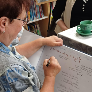 Na zdjęciu jedna pani dokonuje pamiatkowego wpisu do nowej kroniki biblioteki w Torzymiu. 